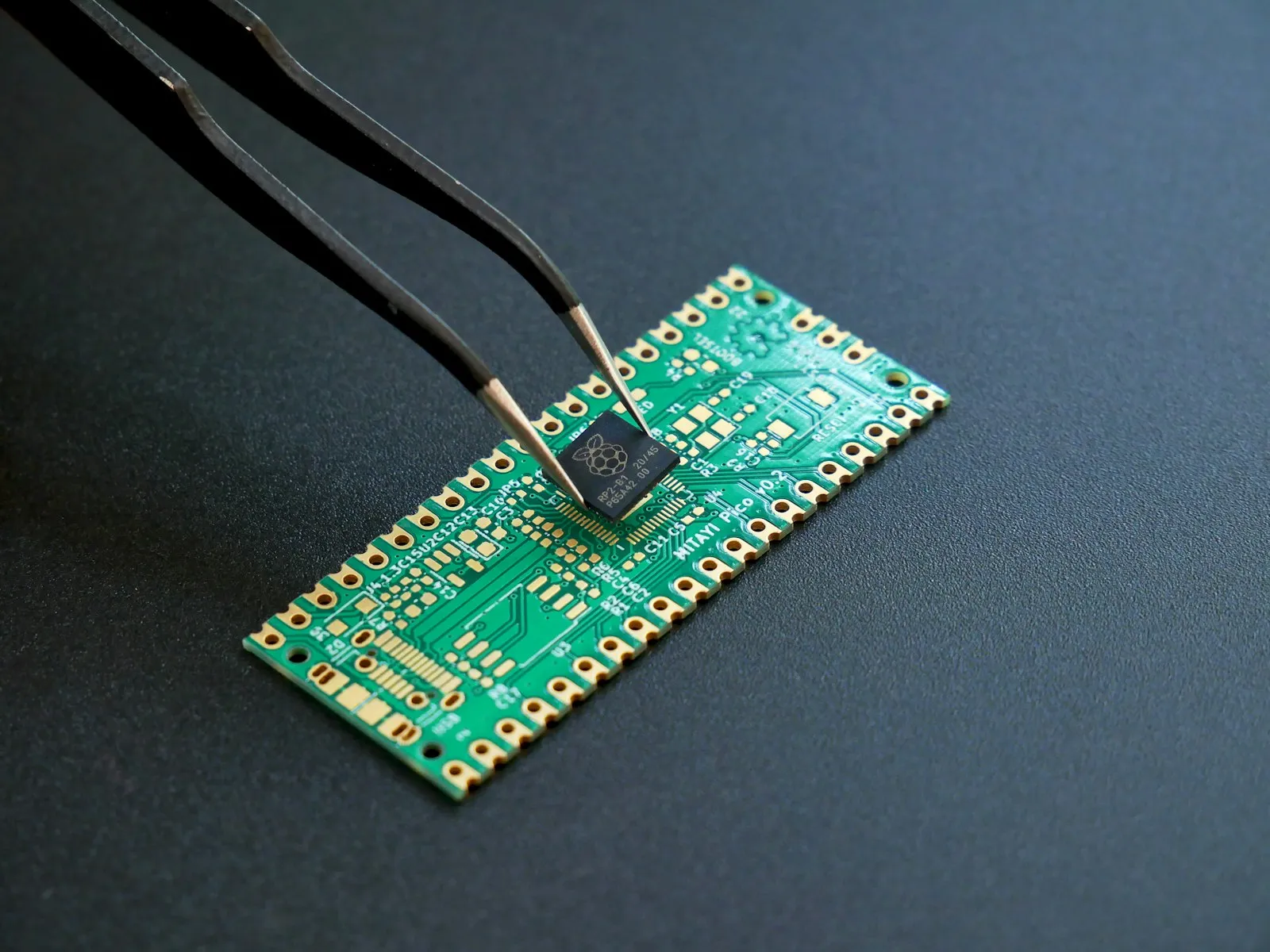 Pinzas colocando un microcontrolador sobre una placa de circuito impreso